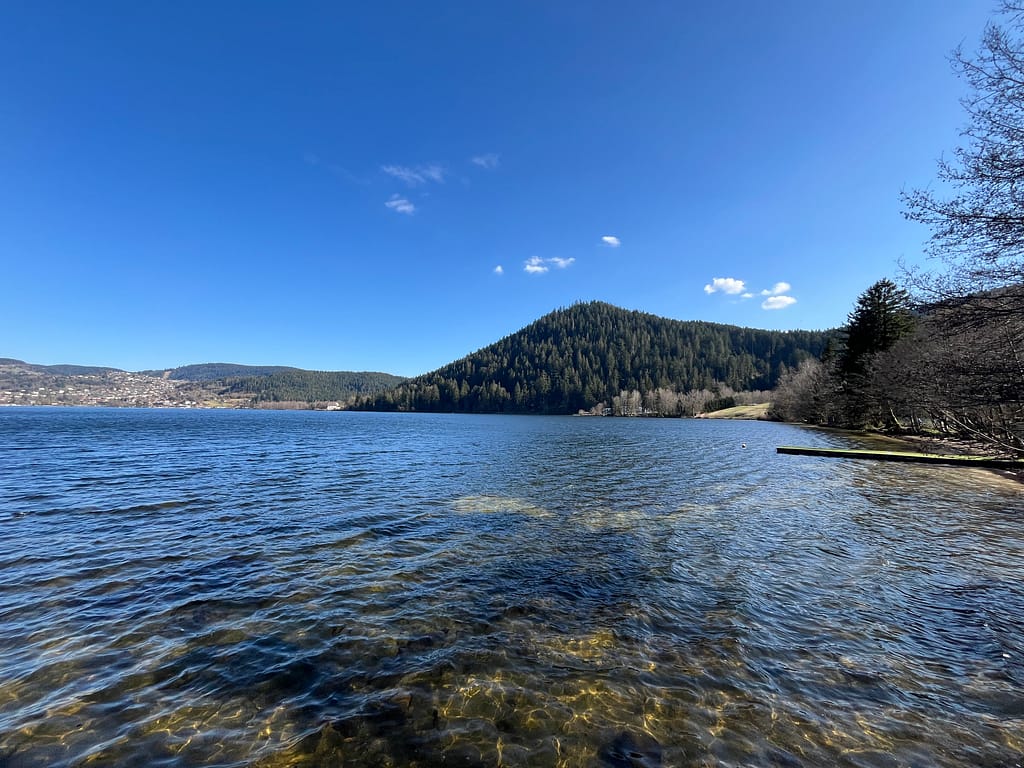 Vue panoramique du Lac de Gérardmer sous le soleil, situé à seulement 10 minutes de la location La Grande Cabane du Blanc Ruxel. Vue panoramique du Lac de Gérardmer sous le soleil, situé à seulement 10 minutes de la location La Grande Cabane du Blanc Ruxel.